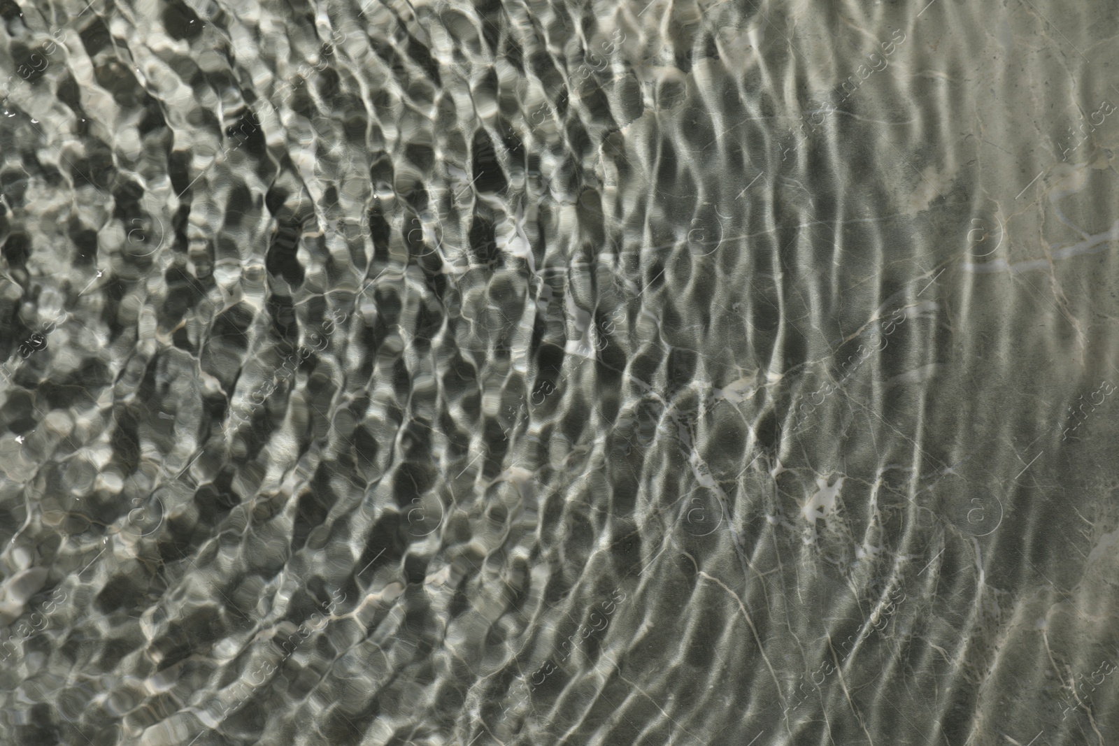 Photo of Rippled surface of clear water on light grey textured background, top view