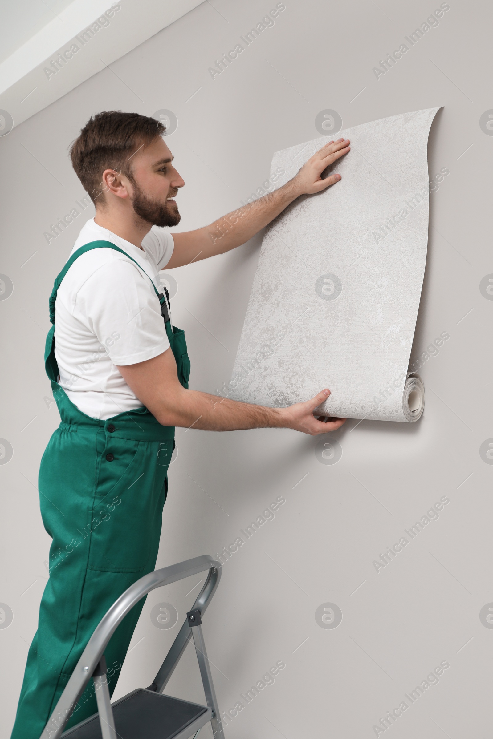 Photo of Worker hanging stylish wall paper sheet indoors