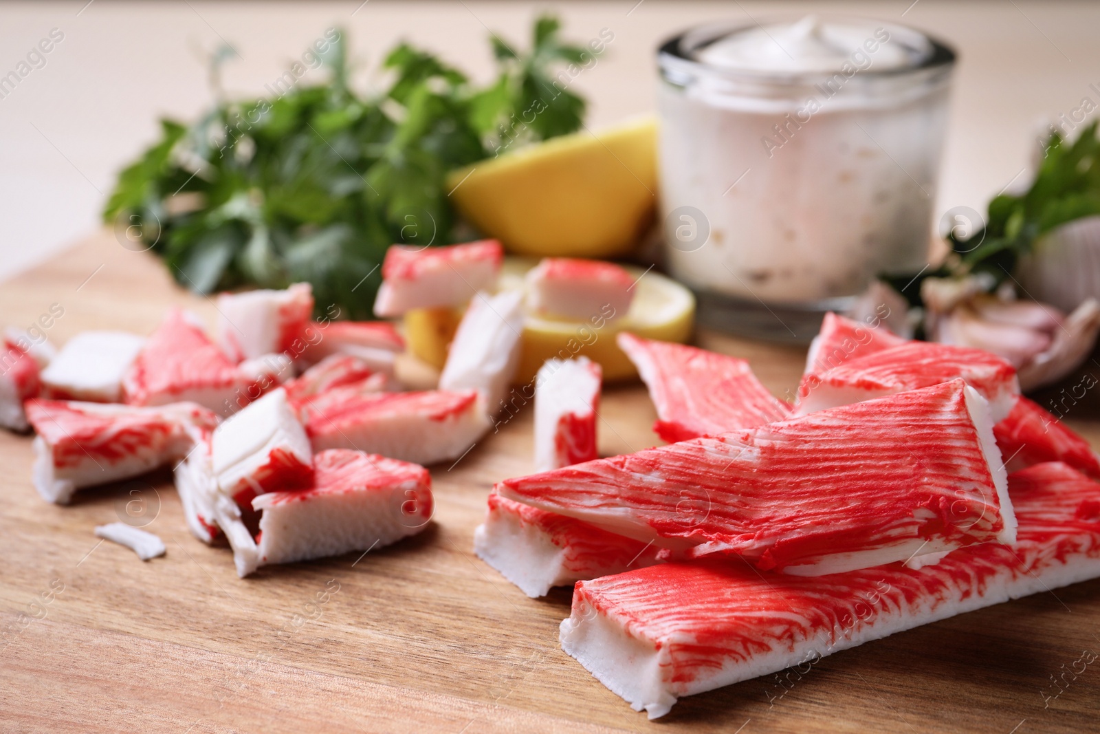 Photo of Delicious crab sticks on wooden board, closeup