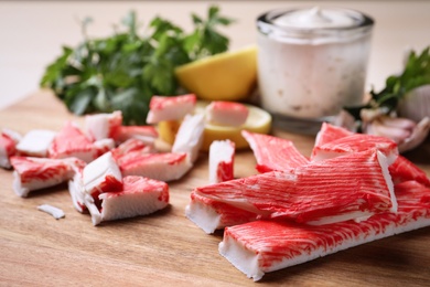 Photo of Delicious crab sticks on wooden board, closeup