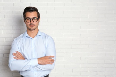 Photo of Young male teacher with glasses near brick wall. Space for text