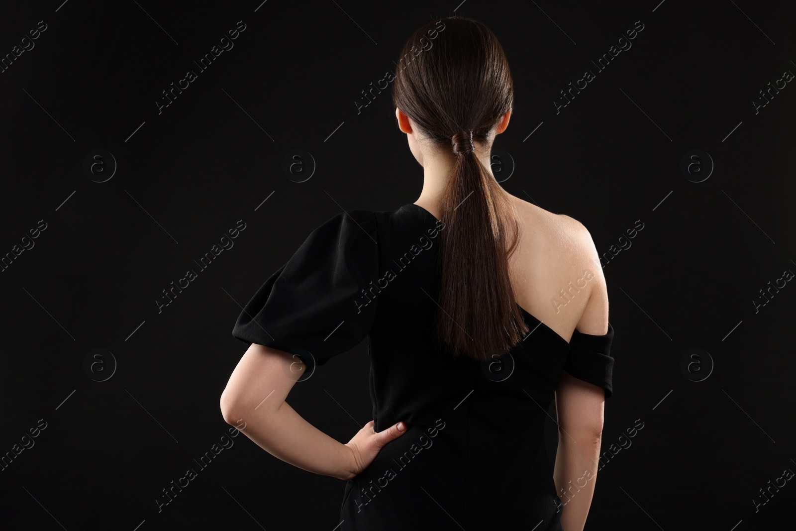 Photo of Woman in elegant dress on black background, back view