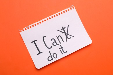 Photo of Motivation concept. Changing phrase from I Can't Do It into I Can Do It by crossing out letter T on orange background, top view