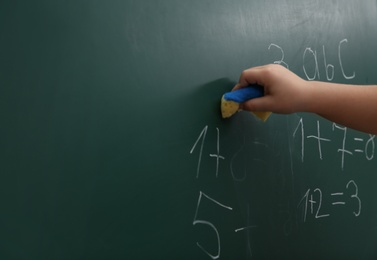 Photo of Little child wiping math sums from chalkboard, closeup. Space for text