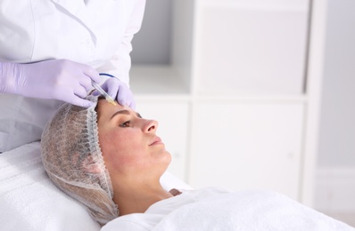 Woman undergoing face biorevitalization procedure in salon. Cosmetic treatment