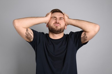 Photo of Man suffering from migraine on grey background
