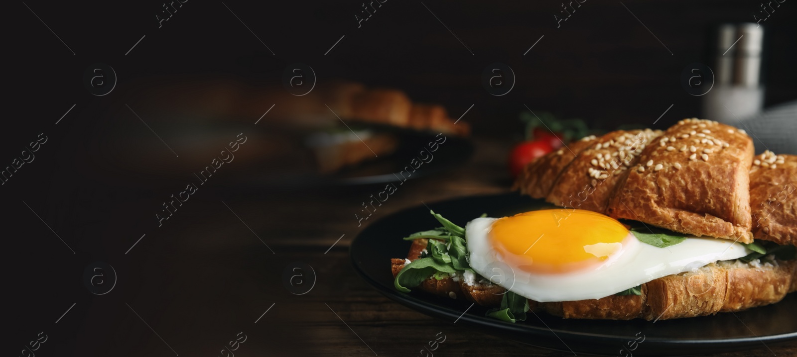 Image of Delicious croissant with arugula and fried egg on wooden table, space for text. Banner design