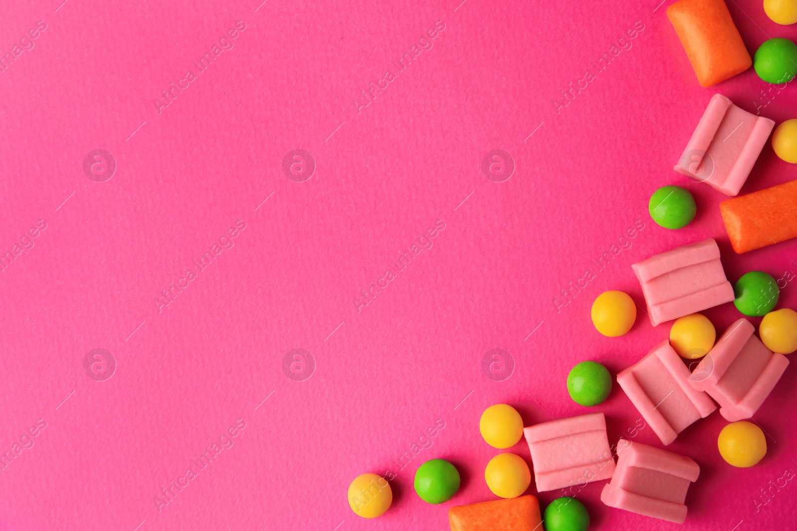 Photo of Many different chewing gums on pink background, flat lay. Space for text