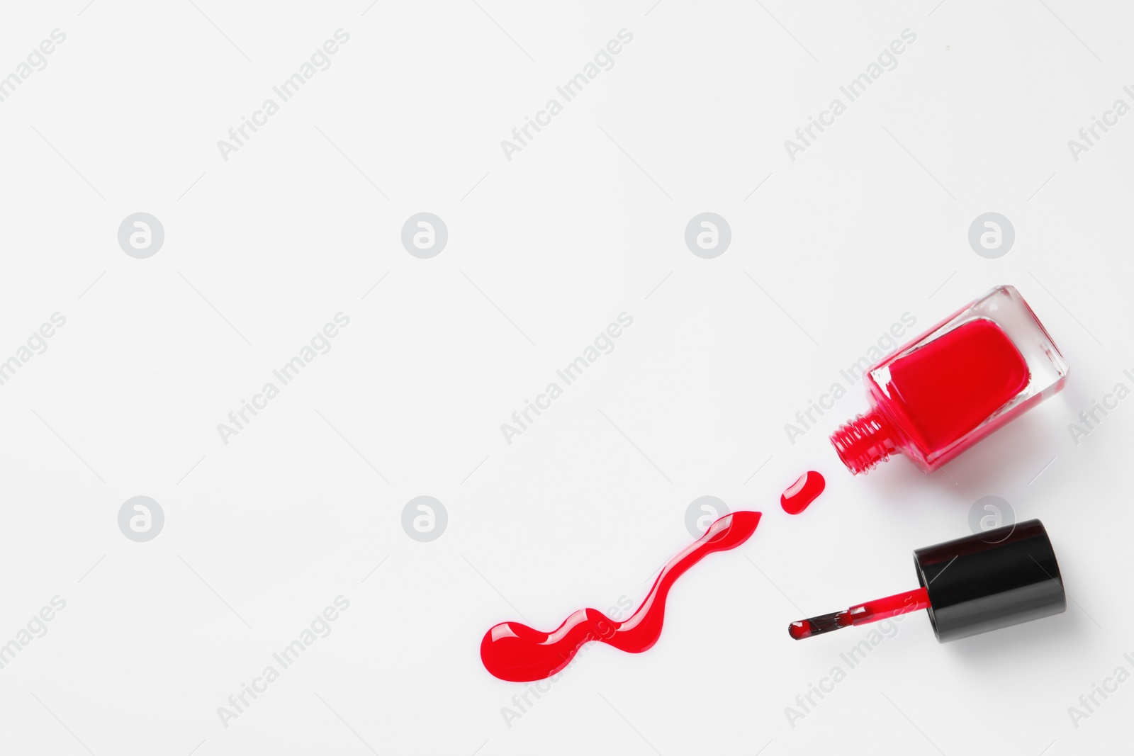 Photo of Spilled color nail polish with bottle and brush on white background, top view