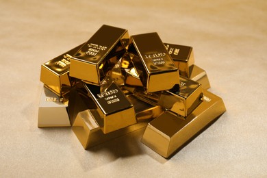 Photo of Many shiny gold bars on color background