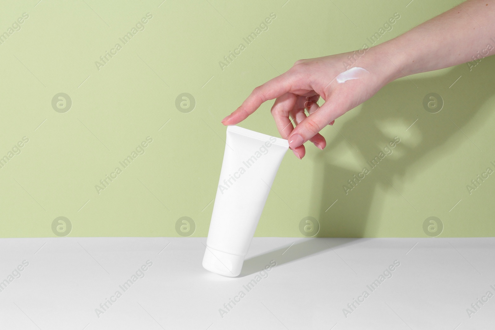 Photo of Woman with tube of cream on color background, closeup