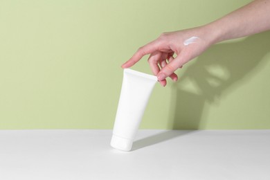 Woman with tube of cream on color background, closeup