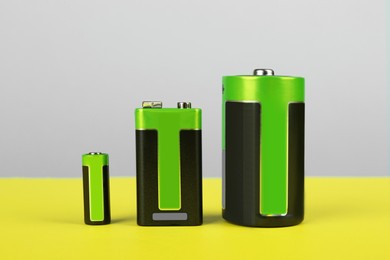 Different types of batteries on color background