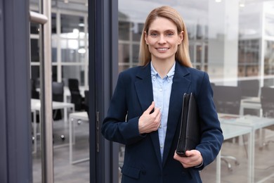 Photo of Female real estate agent with leather portfolio near office outdoors