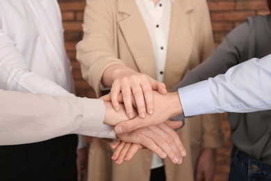 Photo of Group of people holding their hands together indoors, closeup