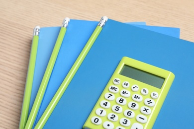 Photo of Calculator, notebooks and pencils on wooden table, closeup. Tax accounting