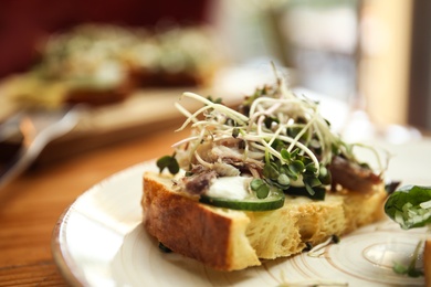 Delicious bruschetta with fish on wooden table, closeup