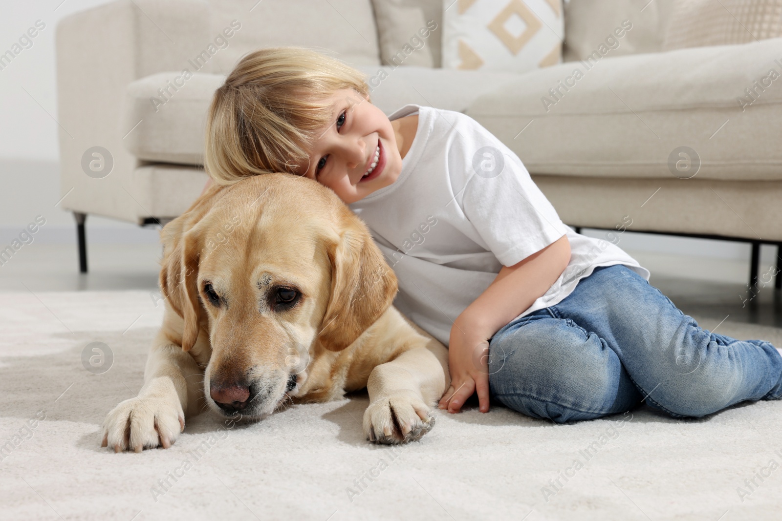 Photo of Cute little child with Golden Retriever on floor at home. Adorable pet