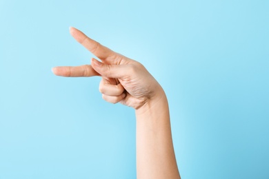 Woman showing P letter on color background, closeup. Sign language