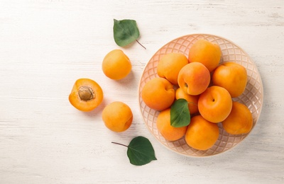 Composition with delicious ripe apricots on white wooden background, top view. Space for text