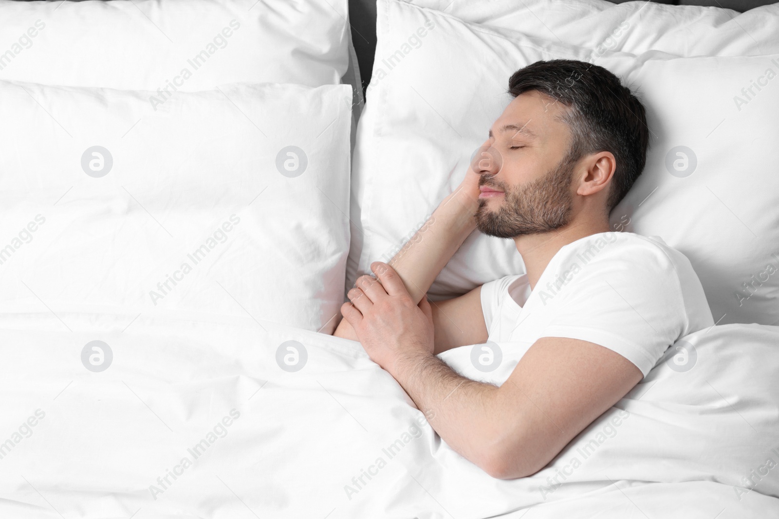 Photo of Handsome man sleeping in soft bed, above view