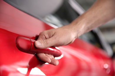 Photo of Man opening door of new car, closeup