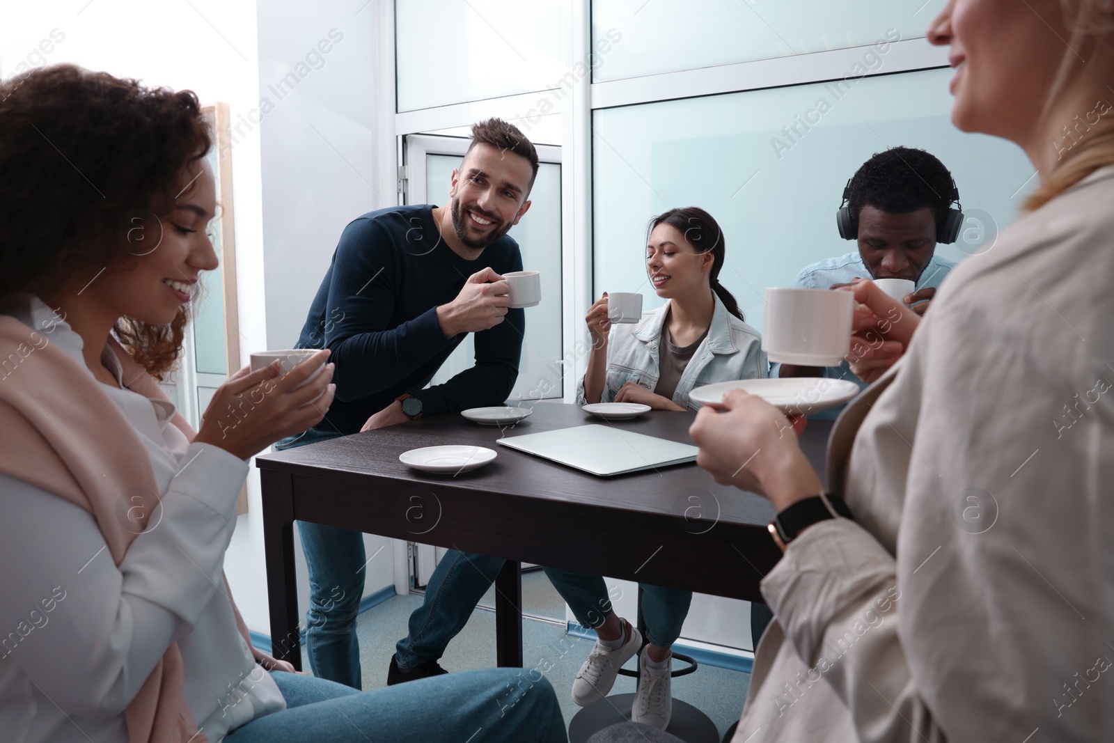 Photo of Team of employees enjoying coffee break together in office. Startup project