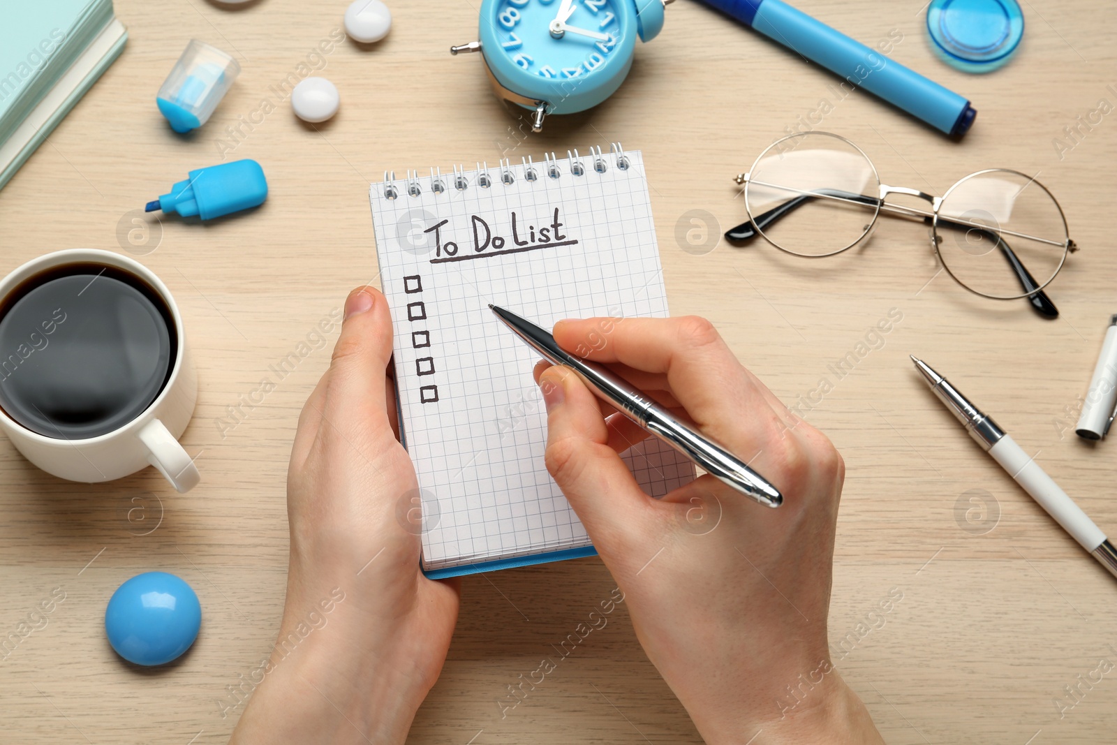 Photo of Woman filling To Do list in notepad at wooden table, top view