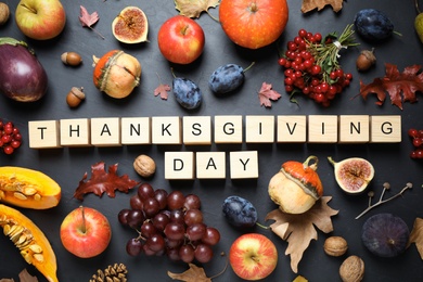 Photo of Cubes with phrase THANKSGIVING DAY, autumn fruits and vegetables on dark background, flat lay. Happy holiday