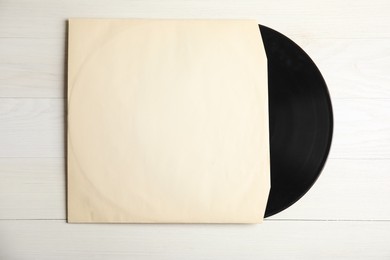 Photo of Vintage vinyl record in paper sleeve on white wooden table, top view