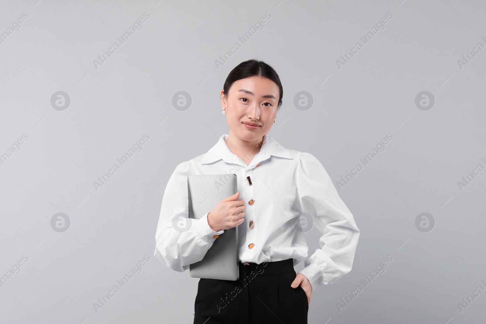 Photo of Portrait of beautiful businesswoman with laptop on grey background