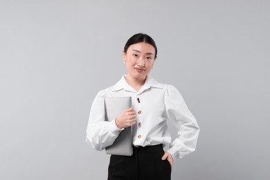 Portrait of beautiful businesswoman with laptop on grey background