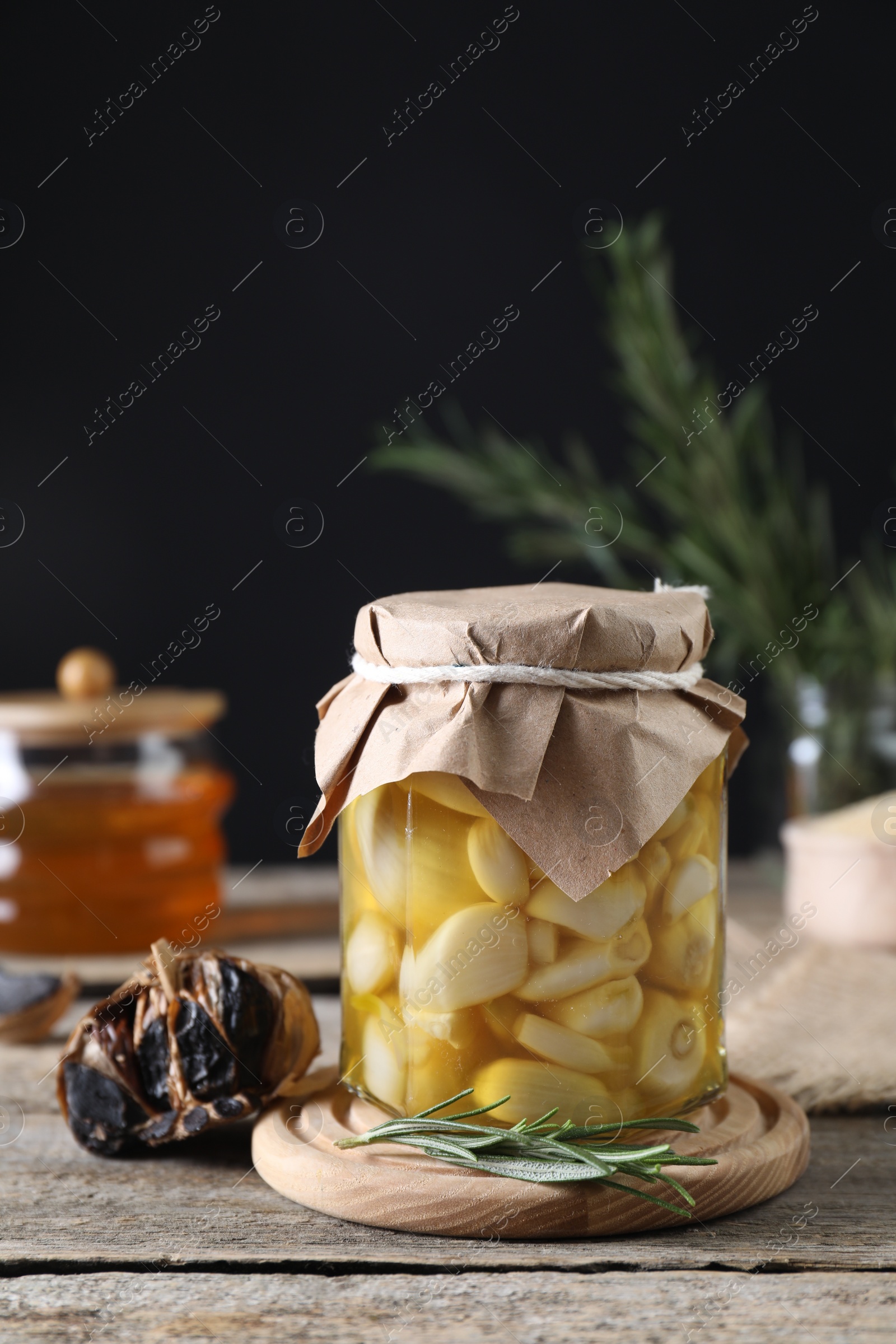 Photo of Garlic with honey in glass jar and fermented black garlic on wooden table