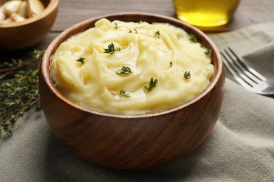 Photo of Bowl of delicious mashed potato with thyme on grey tablecloth, closeup