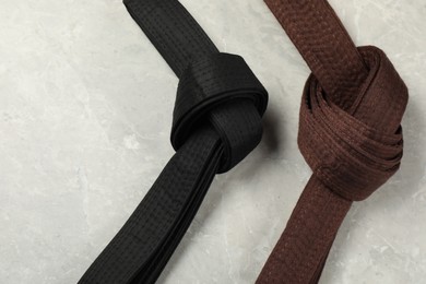 Photo of Black and brown karate belts on gray marble background, flat lay. Space for text