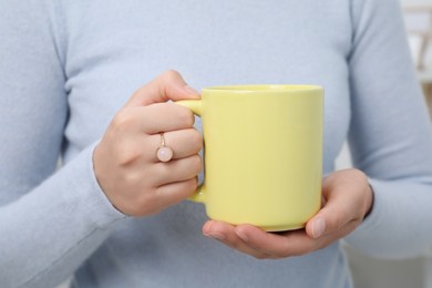 Photo of Closeup view of woman holding yellow mug. Mockup for design
