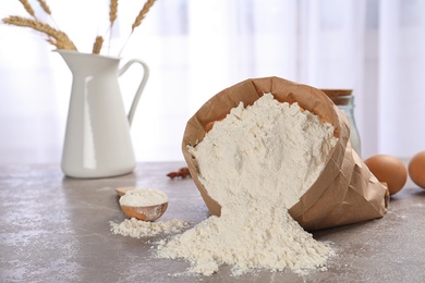 Photo of Paper bag and spoon with flour on table