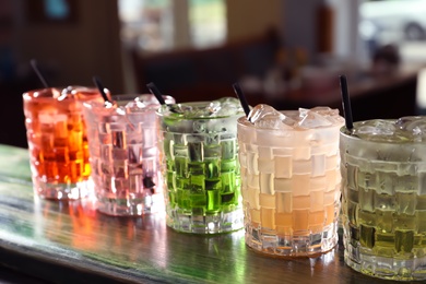 Photo of Glasses of delicious cocktails with ice on table