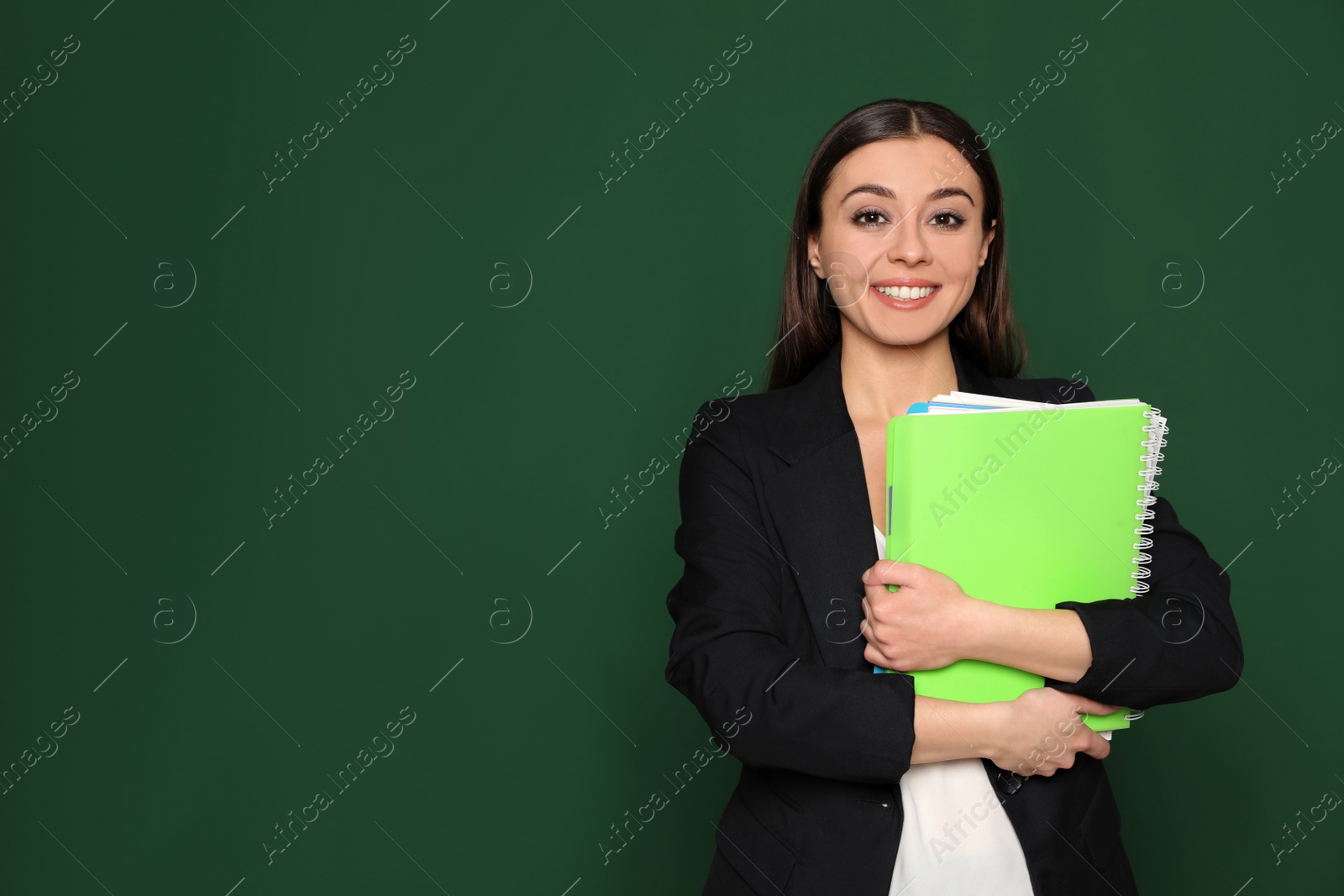 Photo of Portrait of young teacher with notebooks on green background. Space for text