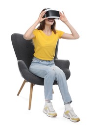 Smiling woman using virtual reality headset while sitting in armchair against white background