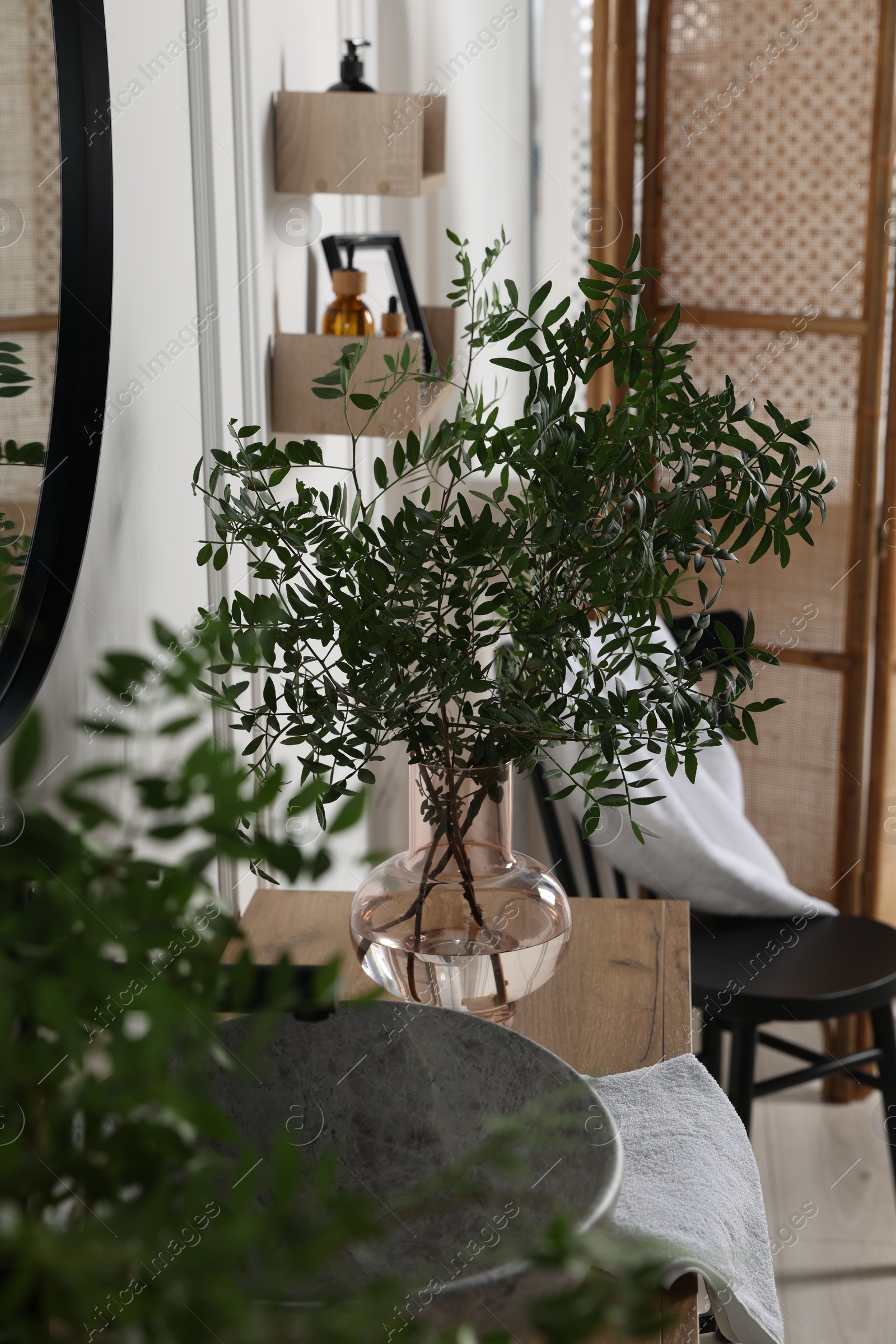 Photo of Eucalyptus branches and towel near stylish vessel sink on bathroom vanity. Interior design