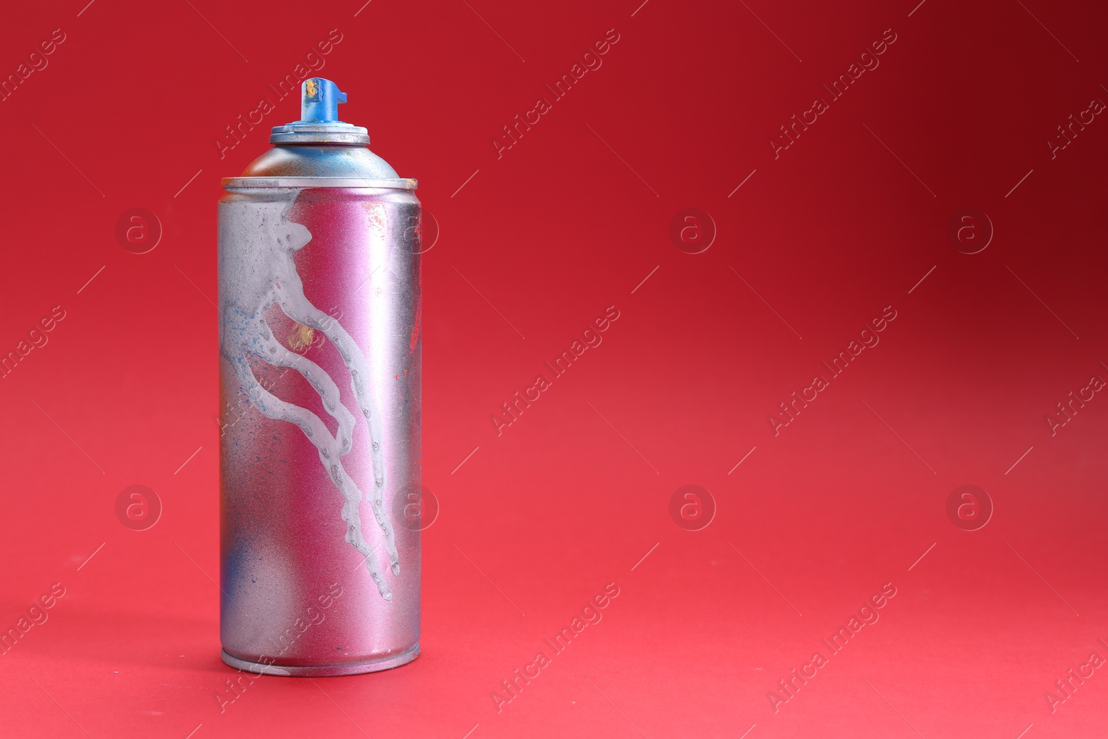 Photo of One can of bright spray paint on red background, space for text