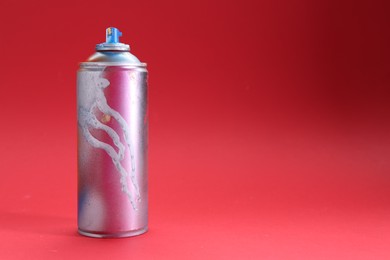 Photo of One can of bright spray paint on red background, space for text