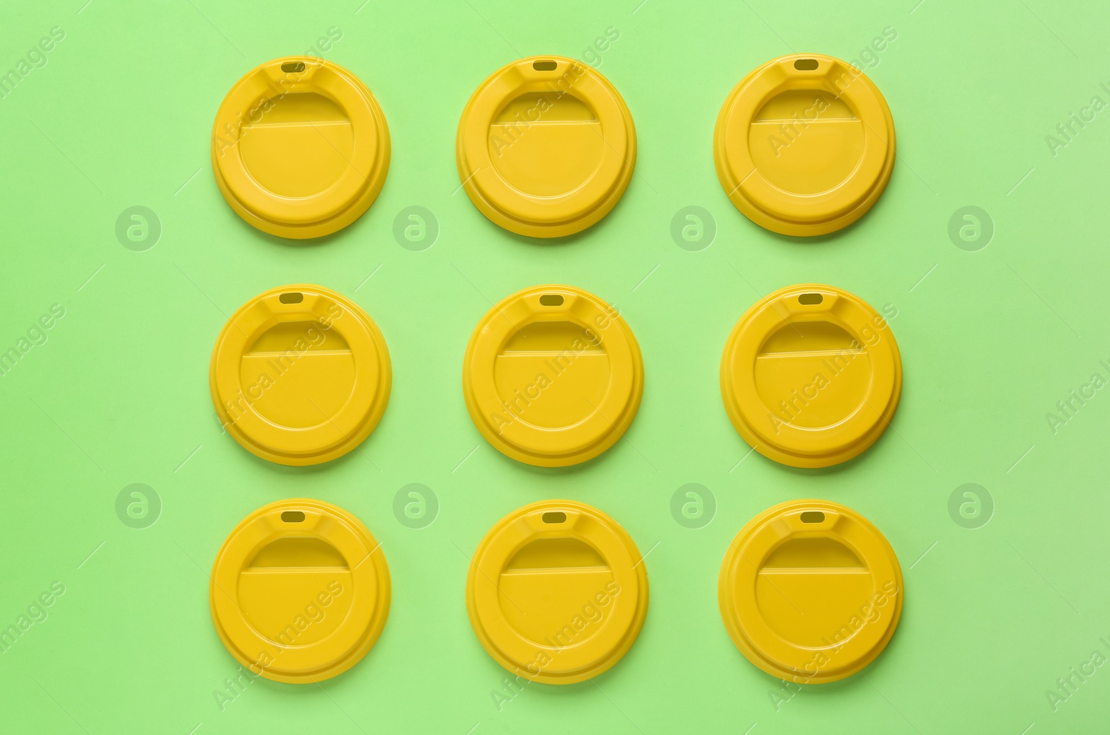 Photo of Plastic caps for disposable cups on green background, flat lay