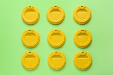 Photo of Plastic caps for disposable cups on green background, flat lay