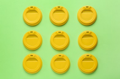 Plastic caps for disposable cups on green background, flat lay