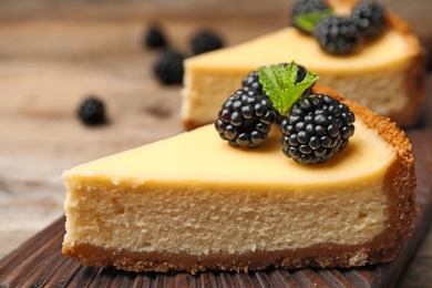 Piece of delicious cheesecake decorated with blackberries on table