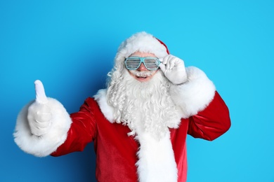 Photo of Authentic Santa Claus wearing funny glasses on color background