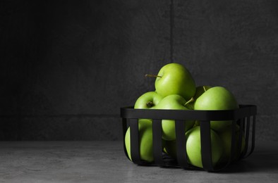 Photo of Black metal container full of apples on table against dark grey background, space for text