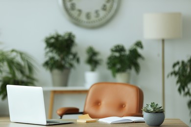 Comfortable workplace with modern laptop on wooden table in room. Interior design